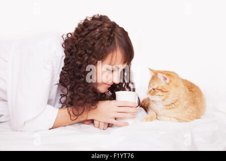 Donna con una tazza di caffè e un gatto nel letto Foto Stock