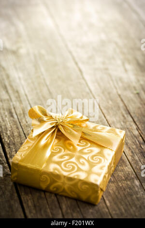 Gold confezione regalo sul vecchio tavolo in legno Foto Stock