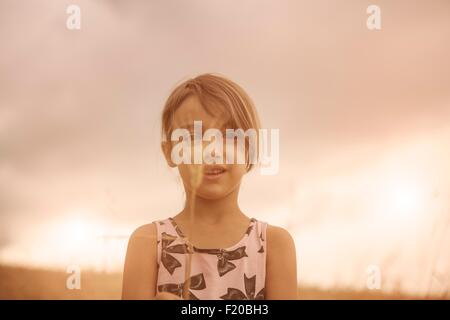 Ritratto di ragazza con chicco di grano di fronte il suo volto nel campo di grano Foto Stock