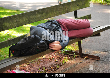 Sleeping ragazzo su una panchina nel parco Foto Stock