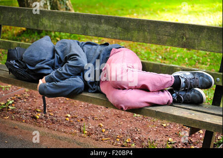 Sleeping ragazzo su una panchina nel parco Foto Stock