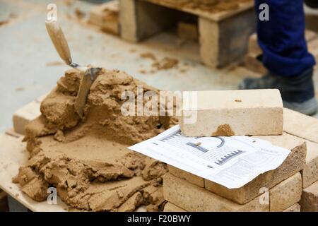 Il cemento, la pila di mattone e blueprint sulla sommità del pallet Foto Stock
