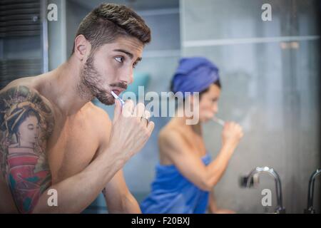 Coppia giovane spazzolare i denti in bagno Foto Stock