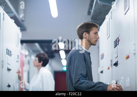 Lo scienziato e il monitoraggio tecnico di pannello di controllo nella sala tecnica Foto Stock