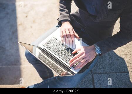 Ritagliata ad alto angolo di visione del giovane uomo utilizzando laptop in fase Foto Stock