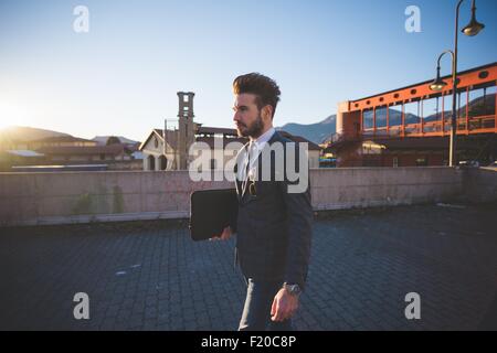 Giovane imprenditore valigetta porta in area urbana Foto Stock