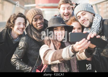 Sei giovani amici adulti tenendo selfie sullo smartphone Foto Stock