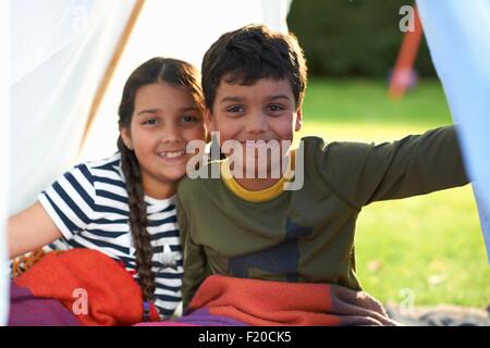 La ragazza e il fratello avvolto in una coperta in tenda fatti in casa Foto Stock