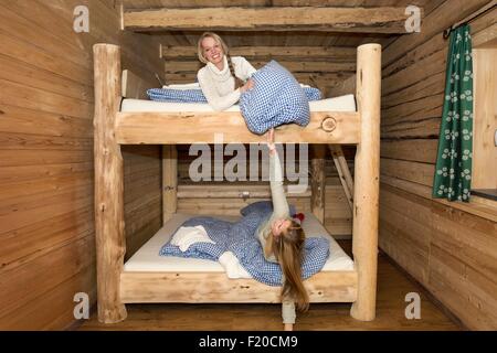 Due giovani donne amici ingannare intorno con cuscini su letti a castello in log cabin Foto Stock