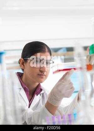 Biologo femmina in laboratorio, tenendo un pallone contenente cellule staminali Foto Stock