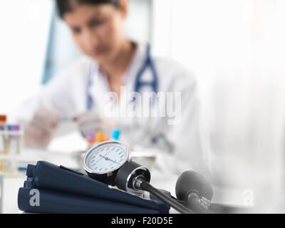 Medico donna esaminando provetta campione alla scrivania in clinica Foto Stock