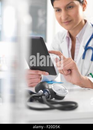 Medico donna utilizzando tavoletta digitale per aggiornare i record medici Foto Stock
