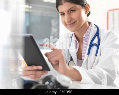 Medico donna utilizzando tavoletta digitale touchscreen per aggiornare i record medici Foto Stock