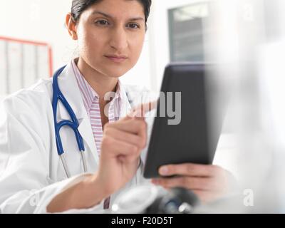 Medico donna utilizzando tavoletta digitale touchscreen per i record medici Foto Stock
