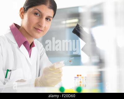 Ritratto di donna scienziato verifica di campioni di sangue utilizzando microscopio Foto Stock