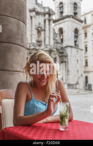 Giovane donna con un cocktail mojito in un ristorante sulla Plaza de la Cattedrale de L Avana, Cuba Foto Stock