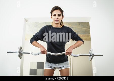 Giovane donna il sollevamento barbell in salotto Foto Stock