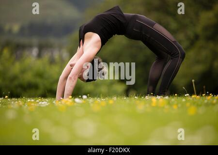 Donna matura la pratica dello yoga si piega all'indietro nel campo Foto Stock