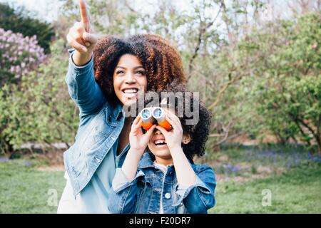 Madre e figlia con il binocolo, guardando in alto, puntando Foto Stock