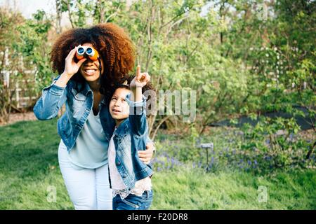 Madre e figlia con il binocolo, guardando in alto, puntando Foto Stock