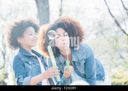 Madre e figlia a soffiare bolle insieme Foto Stock