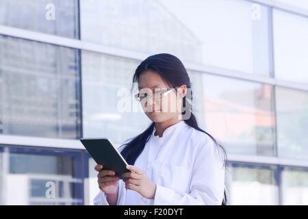 Giovane donna scienziato lettura digitale compressa al di fuori del laboratorio Foto Stock