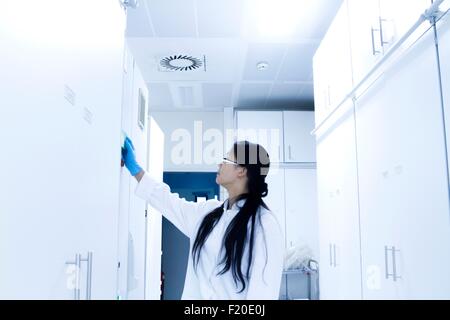 Donna scienziato apertura armadio a campione in laboratorio Foto Stock