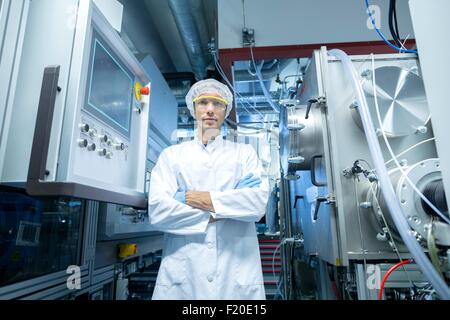 Ritratto di uno scienziato maschio con i bracci ripiegati in lab cleanroom Foto Stock