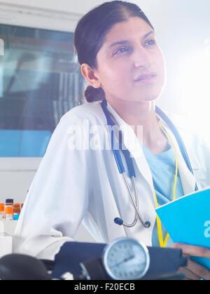 Medico donna contemplando note mediche in ospedale Foto Stock