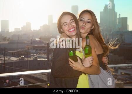 Ritratto di due giovani donne abbracciando presso il bar sul tetto con Los Angeles skyline, STATI UNITI D'AMERICA Foto Stock