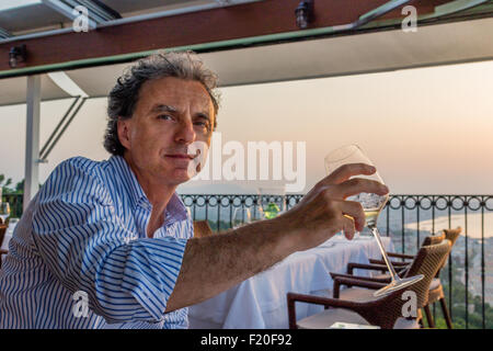 Momenti magici da condividere come una tranquilla cena presso il ristorante che si affaccia sul mare al tramonto: Nizza uomo di mezza età è di andare a bere Foto Stock