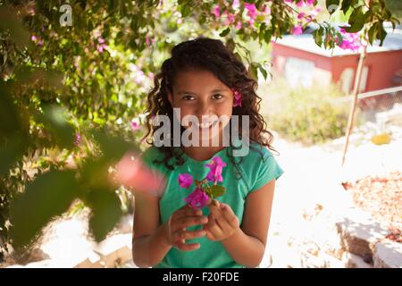 Ritratto di ragazza in giardino azienda fiore rosa Foto Stock