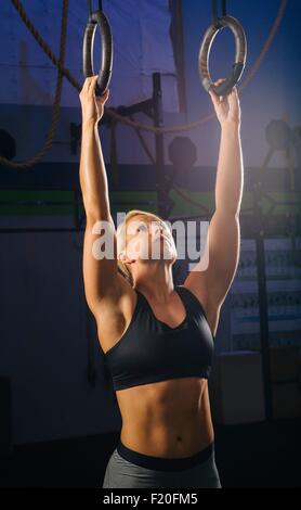 Giovane donna preparazione al treno su anelli di palestra Foto Stock