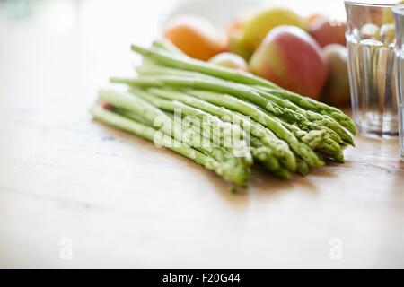 Asparagi, frutti, bicchiere sul tavolo da pranzo Foto Stock