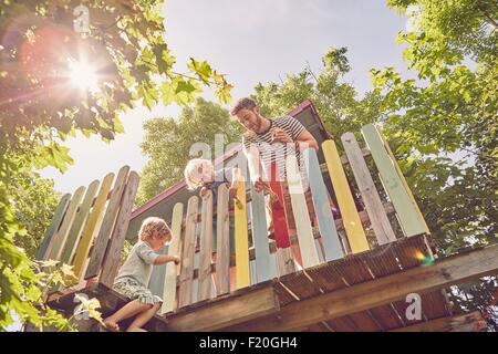Padre e i due figli, pittura tree house, a basso angolo di visione Foto Stock