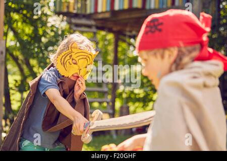 Due giovani fratelli in giardino, indossando costumi e giocare con la finta di spade Foto Stock