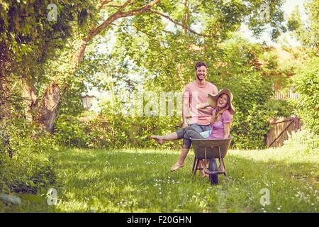 Coppia giovane, uomo donna di spinta in carriola, ridendo Foto Stock