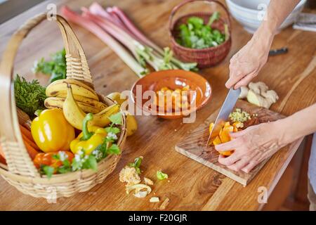 Donna matura tritare verdure, concentrarsi sulle mani Foto Stock