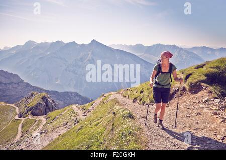 Donna matura escursioni a piedi lungo il sentiero di montagna, Karwendel-Mittenwald, Baviera, Germania Foto Stock