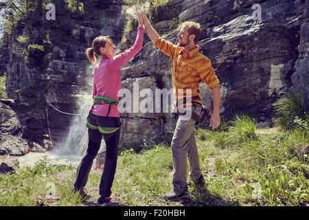 Gli alpinisti dando alta cinque, cascata in background, Ehrwald, Tirolo, Austria Foto Stock