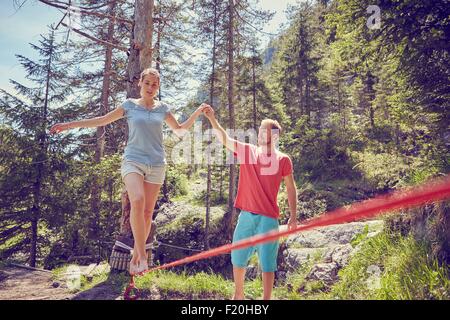 Donna bilanciamento sulla corda con guida da uomo, Ehrwald, Tirolo, Austria Foto Stock