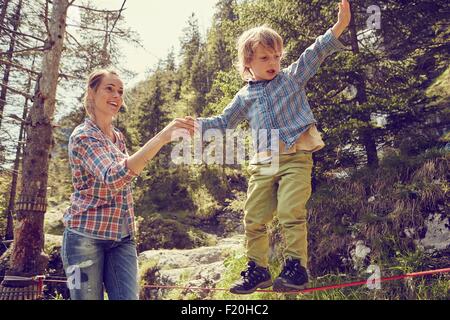 Bilanciamento del ragazzo sulla corda con aiuto dalla madre, Ehrwald, Tirolo, Austria Foto Stock