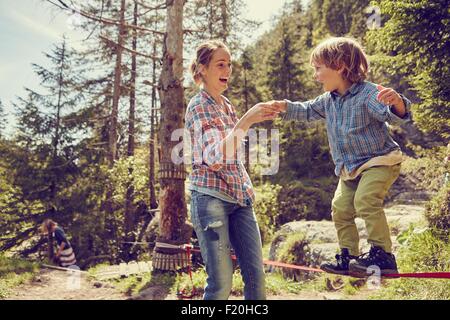 Bilanciamento del ragazzo sulla corda con aiuto dalla madre, Ehrwald, Tirolo, Austria Foto Stock