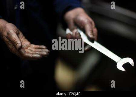 Mani oleoso di tessitore maschio che fissa vecchia macchina di tessitura nel mulino tessile Foto Stock