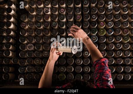 Le mani del pizzo maschio weaver sostituzione filettature sulla vecchia macchina di tessitura nel mulino tessile Foto Stock