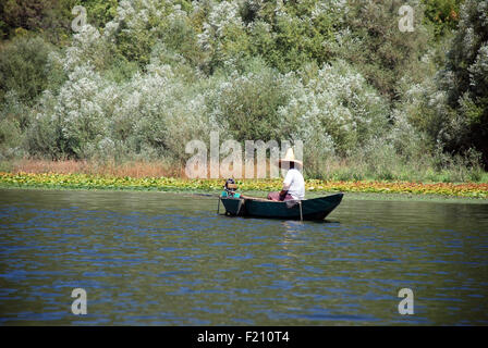 Un uomo in una piccola barca da pesca sul lago di Skadar in Montenegro Foto Stock