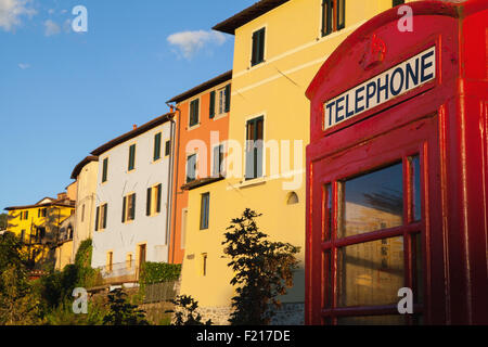 L'Italia, Toscana, Lucca, Barga, British telefono box con facciate delle vecchie case di città in background. Foto Stock