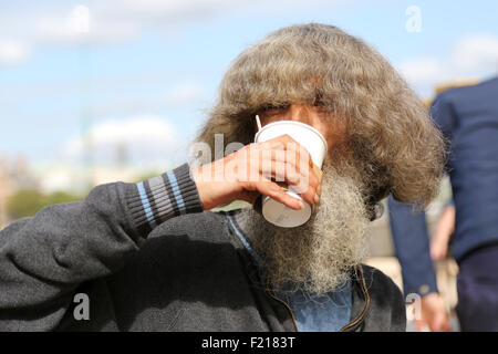 Un eccentrico street persona godendo un take away tazza di tè all'aperto in un pomeriggio soleggiato sulla southbank di Londra a Lambeth Foto Stock