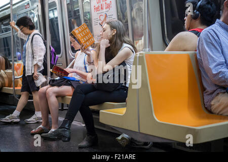 Una donna che legge un libro con la copertina rigida sul treno della metropolitana di New York il sabato, 5 settembre 2015. (© Richard b. Levine) Foto Stock