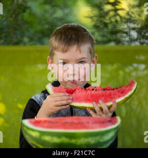 Little Boy mangiare una grande cocomero. Foto Stock